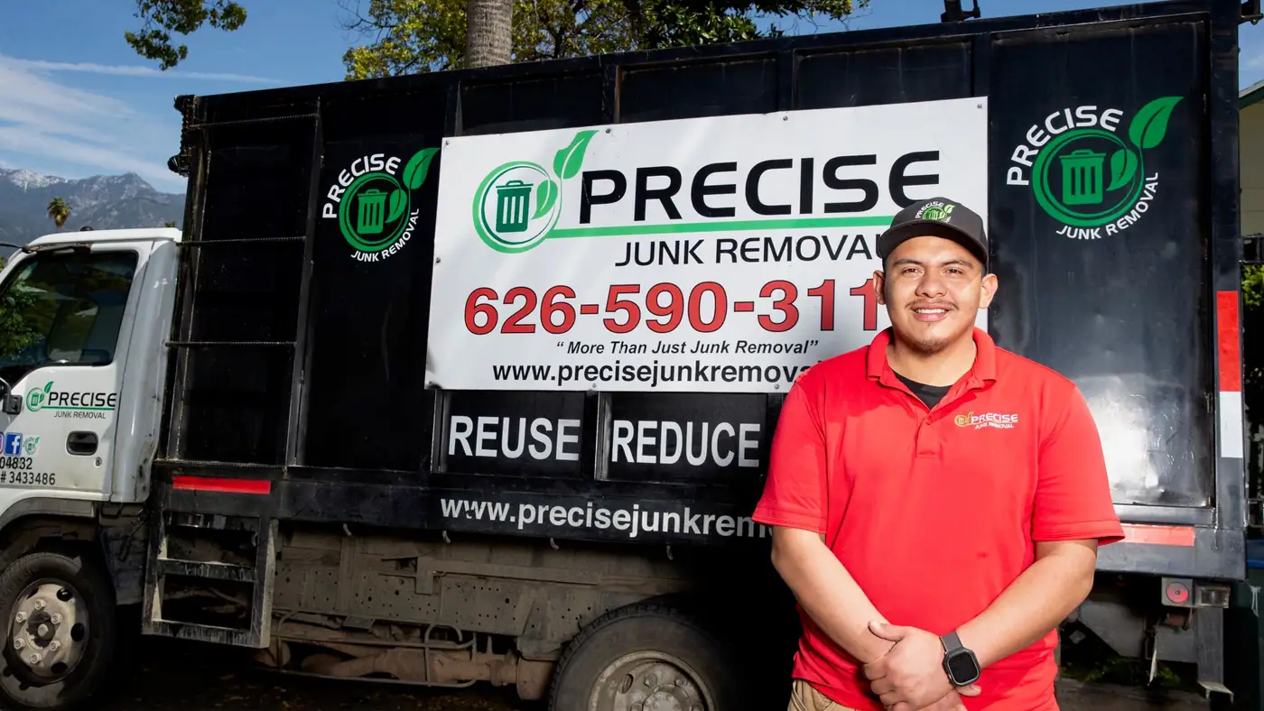 Angel standing beside the Precise Junk Removal truck with its black dump bed and branded side panel