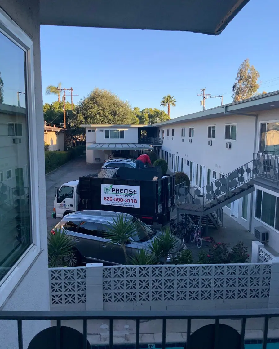 The dump truck parked outside a two story apartment building