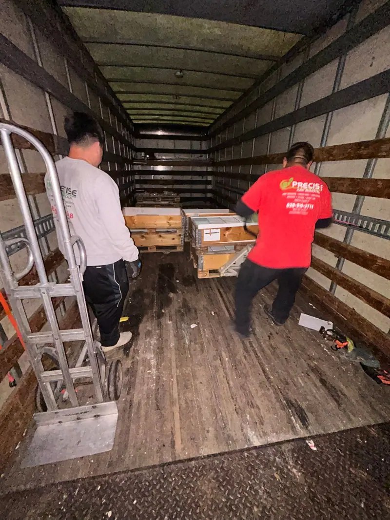 Two crew members in Precise shirts moving crates inside the truck