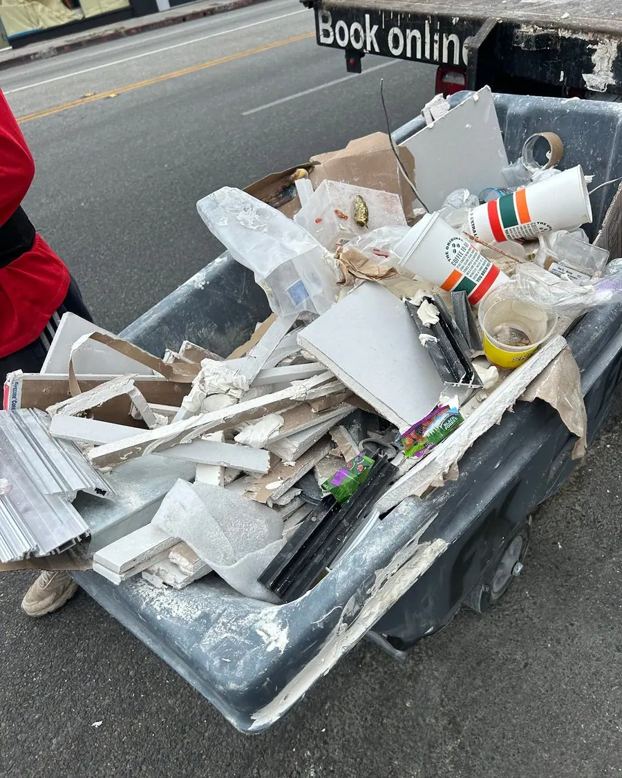 A truck bed filled with broken drywall, buckets and offcuts