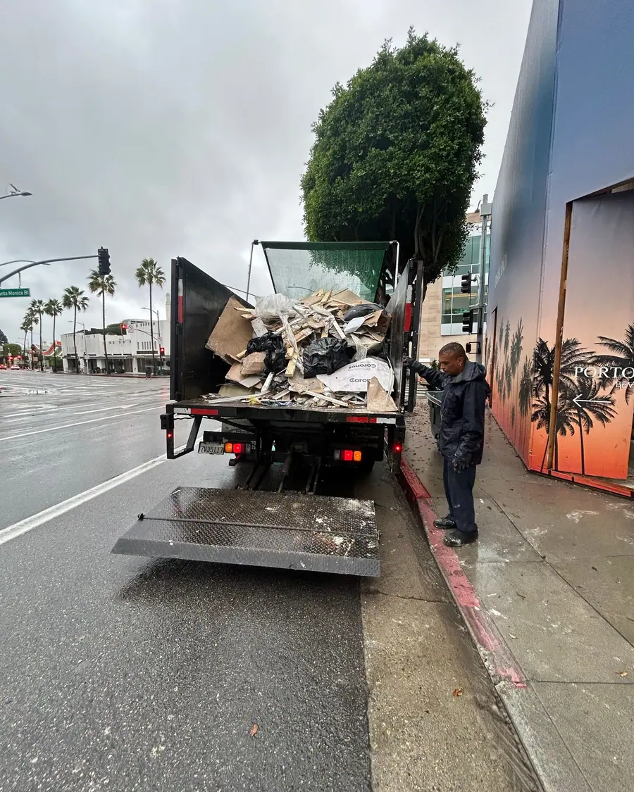 The truck loaded with construction debris at the curb on a wet morning