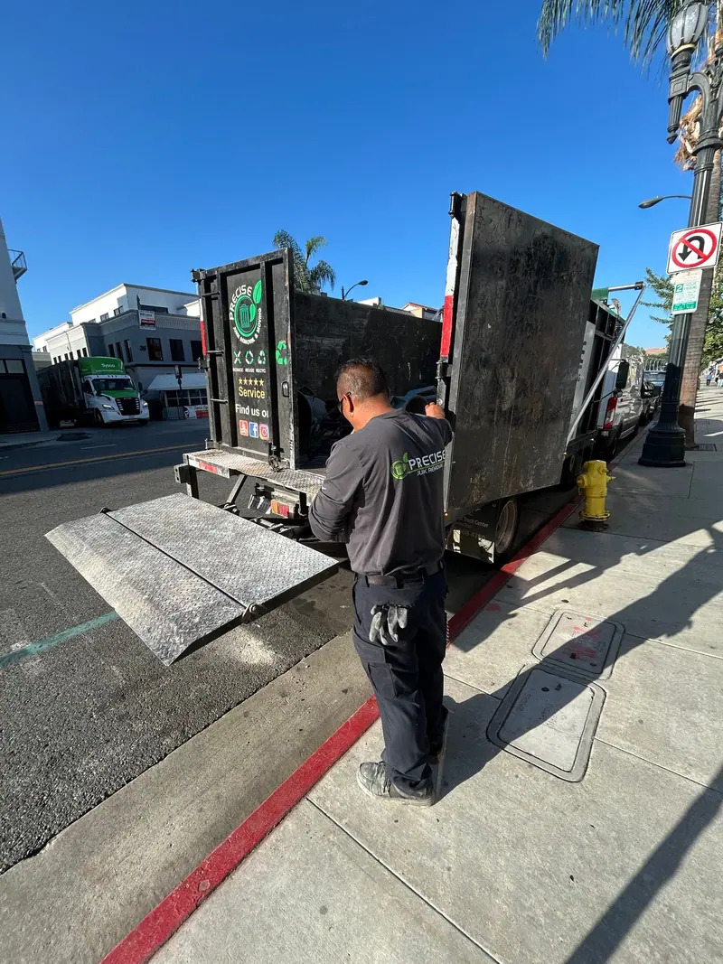 A crew member working the truck liftgate at the curb on a commercial block