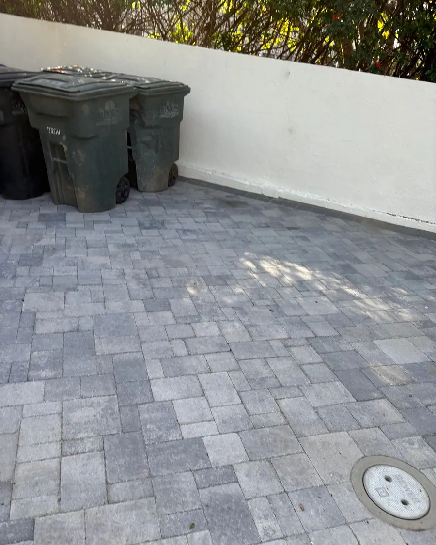 The same paver driveway cleared, with only the wheeled bins left against the wall