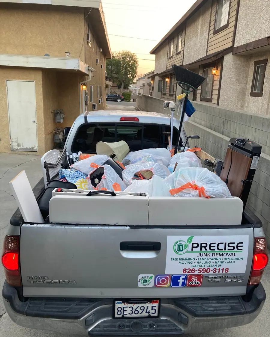 A pickup bed filled with tied bags and boxes in a residential alley
