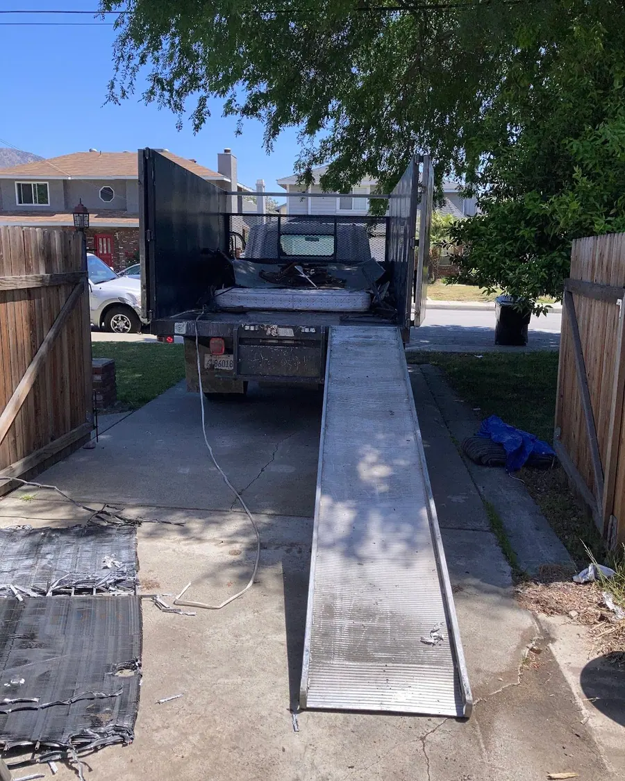 The dump truck with its loading ramp down on a driveway
