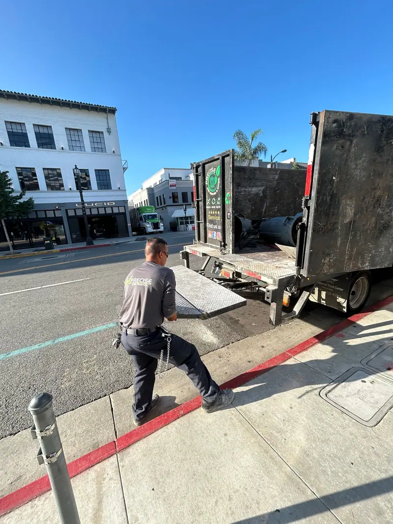 A crew member pulling the loading ramp out of the truck on a downtown street