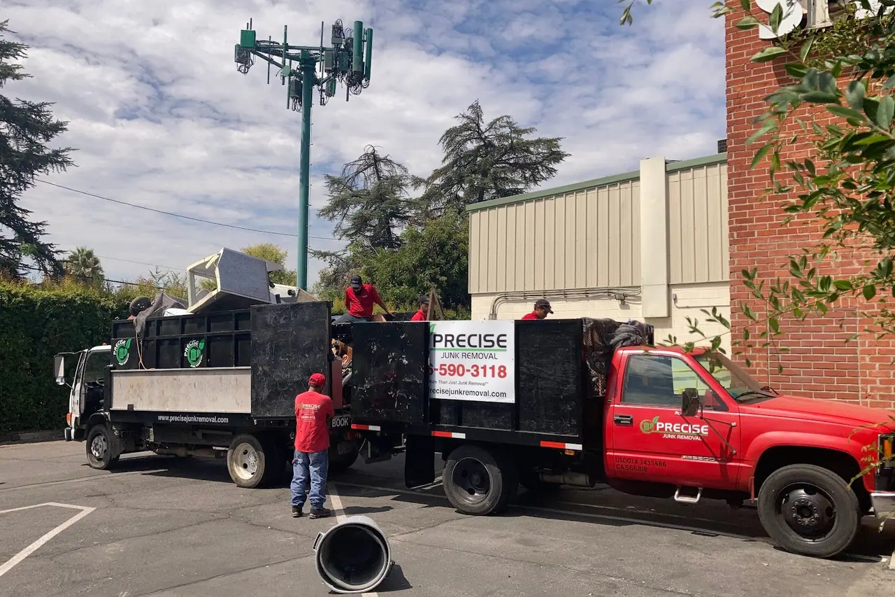 Two Precise trucks parked on a street with crew loading one of them